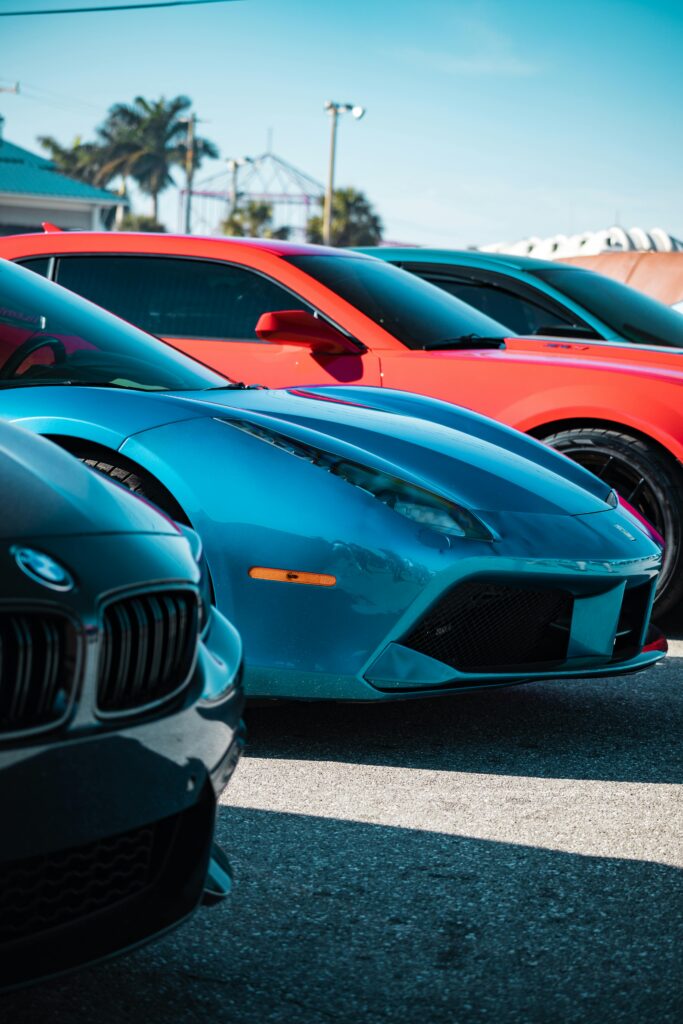 A vibrant lineup of luxury sports cars in various colors parked outdoors in daylight.